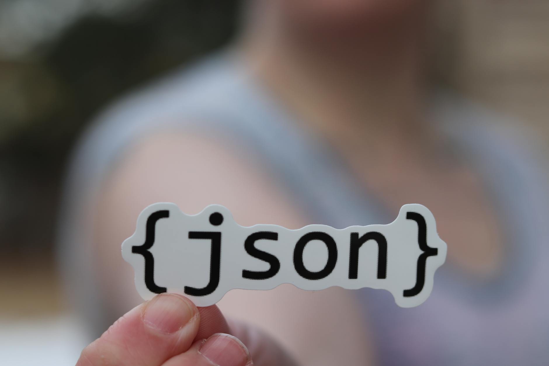 Dłoń trzyma naklejkę z napisem JSON, symbolizującą konfigurację Terraform