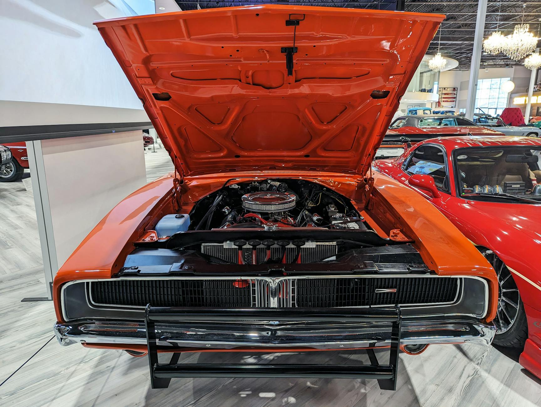 Pomarańczowy klasyczny Dodge Charger z otwartą maską, widoczny silnik