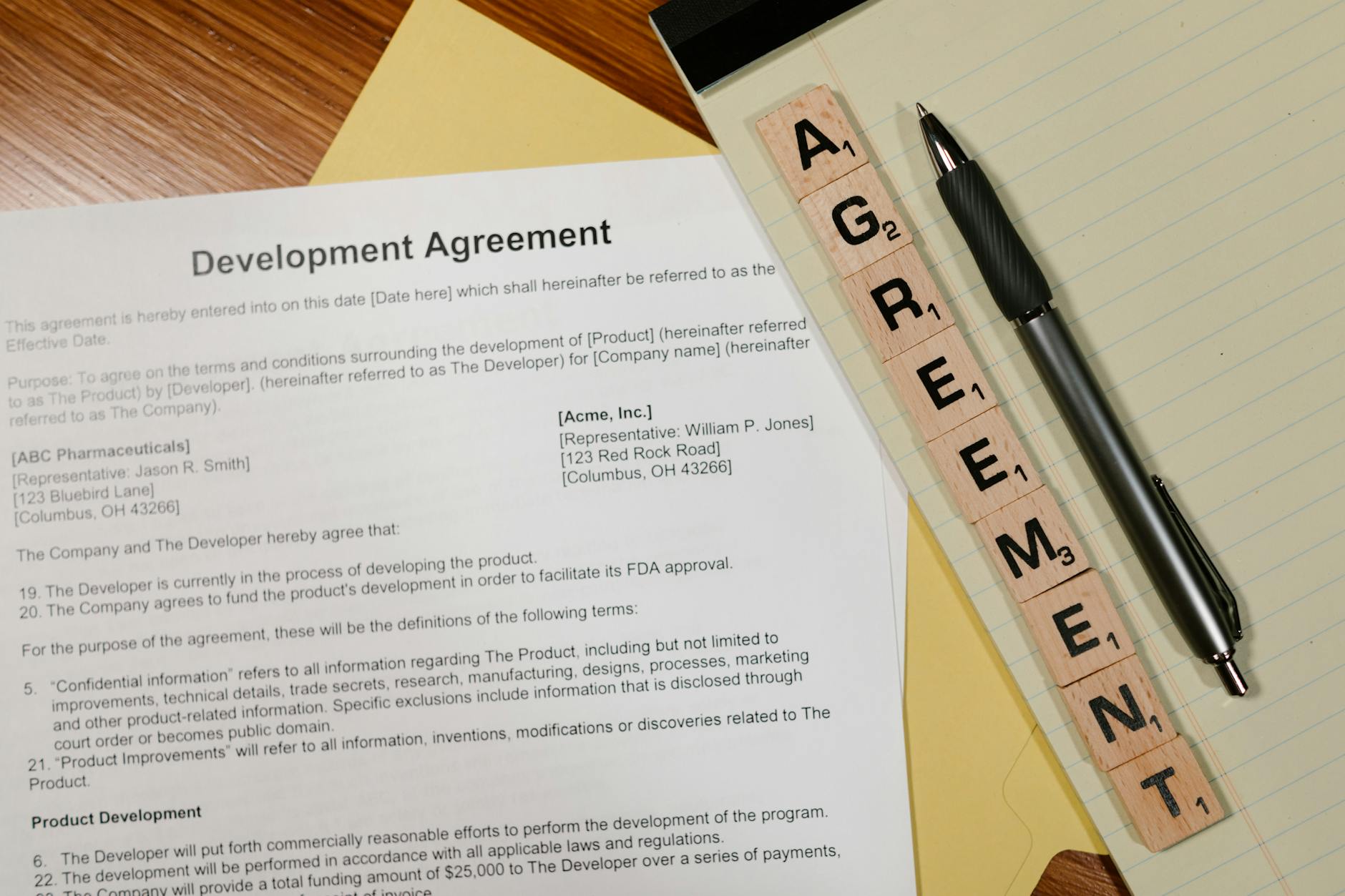 Umowa licencyjna na biurku z długopisem i klockami z napisem AGREEMENT