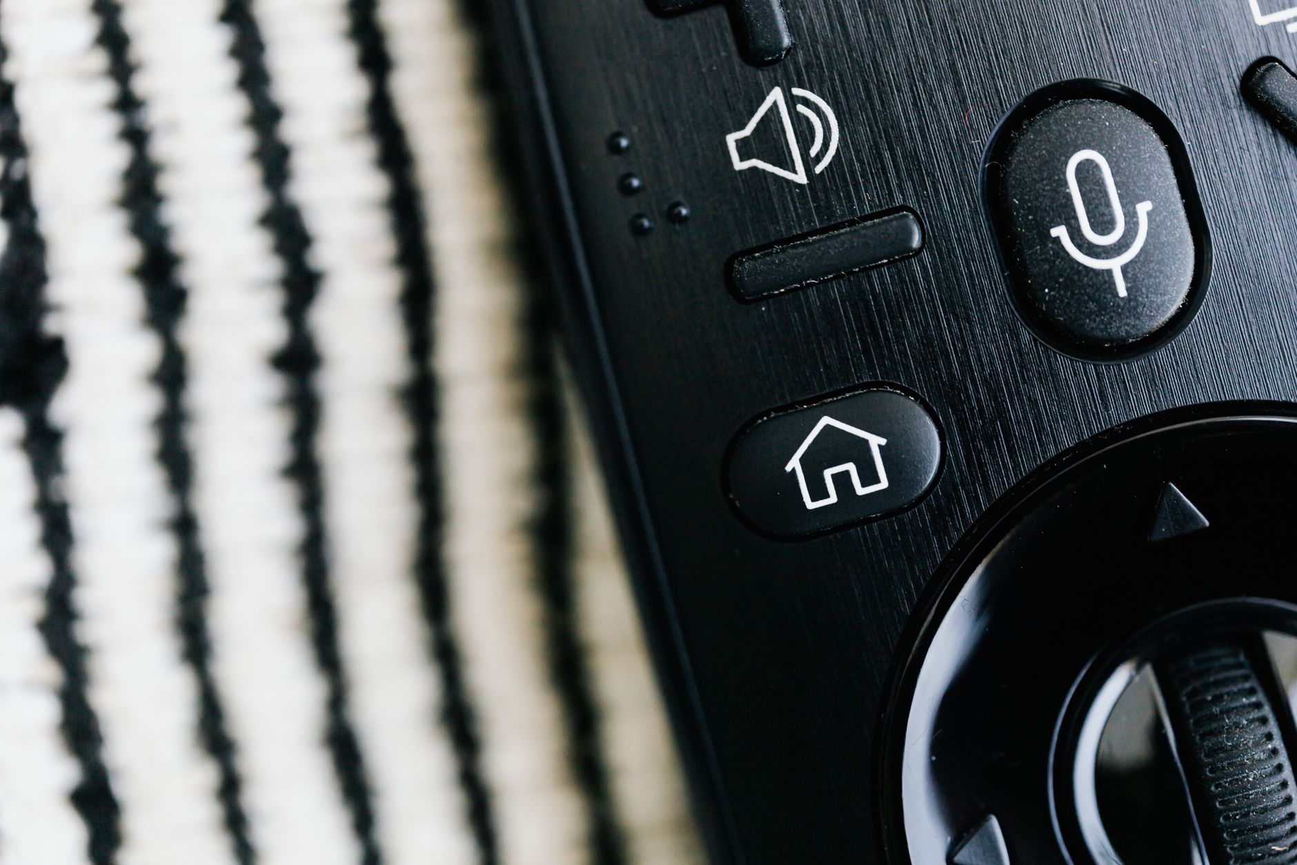 Zigbee, Z Wave czy Wi Fi? Jak wybrać protokół do smart home Czarny pilot z przyciskiem mikrofonu w zbliżeniu na fakturowym tle