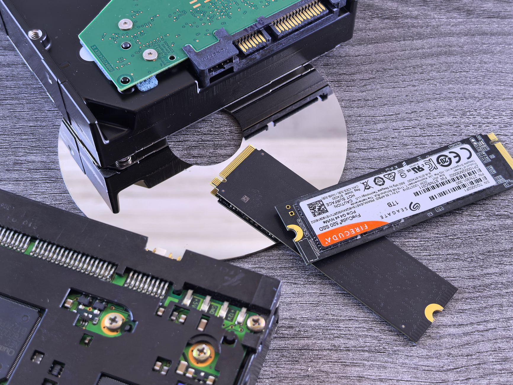 Dysk NVMe SSD, dysk twardy HDD i płyta CD obok siebie